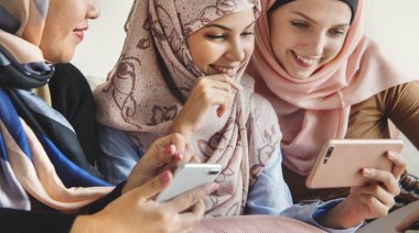 Kanepede oturan ve akıllı telefonlar kullanarak islam kadın grubu 