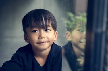 Genç Asyalı çocuk masumiyet sevimli pencerenin yanındaki 