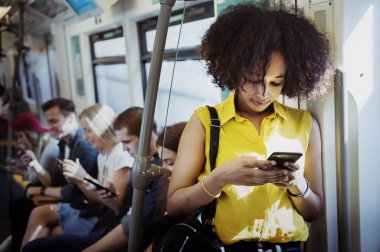 Metroda bir akıllı telefon kullanan genç kadın