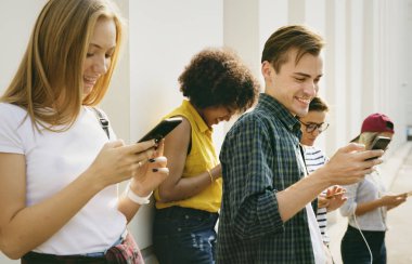 Arkadaşlar açık havada birlikte akıllı telefonlar kullanan ve soğutma