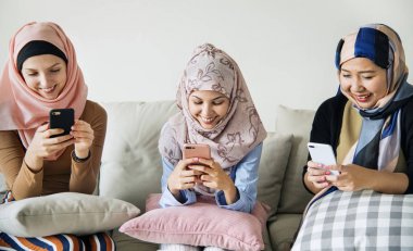 Kanepede oturan ve akıllı telefonlar kullanarak islam kadın grubu 
