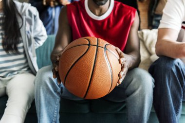 Turuncu basketbol topu ile bankta oturan arkadaşlar