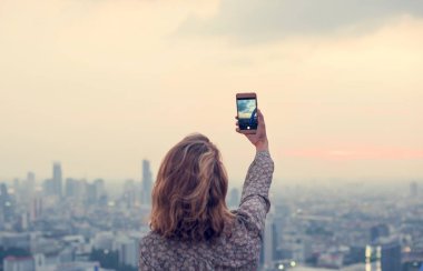 Kadın gün batımının fotoğrafını çekiyor.