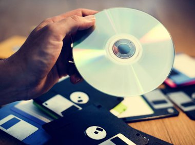 Yumuşak ve sarkık ile CD disk arka plan masaya tutan el