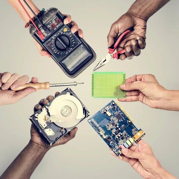 灰色の背景にコンピューター エレクトロニクス部品を保持する手のグループ — ストック写真