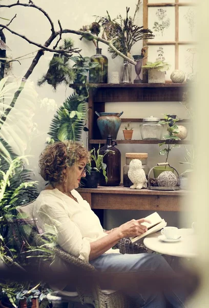 Женщина Расслабляется Читая Книгу Кафе Столом Кофе Растениями — стоковое фото