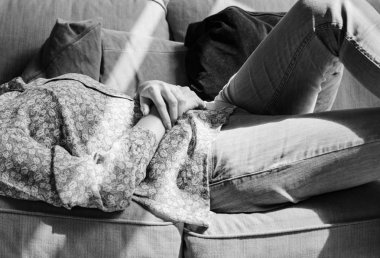 Gri tonlamalı kanepede yatan kadın