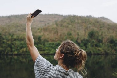 Doğa seyahat ve Turizm kavramı bir fotoğraf çekici yukarıya onun smartphone yükselterek bir kadın el closeup