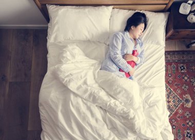 Kadın yatakta sıcak bir paket karnı üzerinde yerleştirme