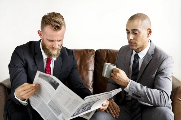 Δύο Επιχειρηματιών Που Κάθεται Στον Καναπέ Εφημερίδα Και Τσάι Κύπελλο — Φωτογραφία Αρχείου