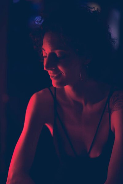 Portrait of woman smiling in a dark bar with red light    