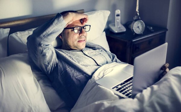 Человек с ноутбуком на кровати
