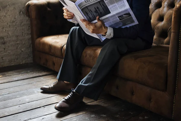 ビジネスマンの新聞を読むと トリミングされた画像のソファに座って — ストック写真