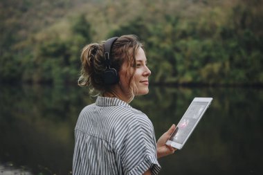 Kulaklıklar ve dijital tablet müzik ve gevşeme ile müzik dinlemek doğada yalnız kadın 