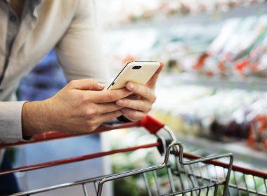 Telefonunu süpermarkette ile oynarken adam