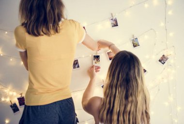 Women with photos hanging with decoration lights on the white wall clipart