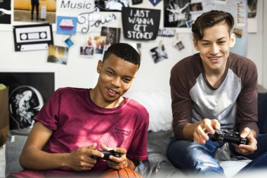 Genç çocukların birlikte video oyunları oynarken bir yatak odasında takılmak