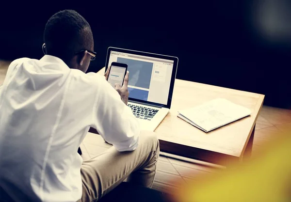 Homem Africano Usando Celular Usando Laptop Mesa — Fotografia de Stock