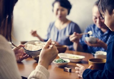 Geleneksel Asya gıda ile masada yemek ve yemek çubukları kullanarak Japon aile