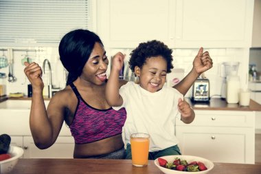 Mother and son eating healthy food in the kitchen clipart