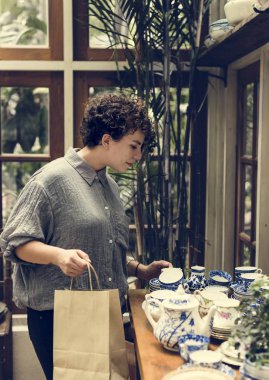 Seramik çay dükkanı seçme ve alışveriş çantası tutarak müşteri kadın