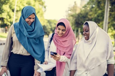 Açık havada yürüyüş ve cep telefonu tarama Müslüman öğrenci kız grubu 