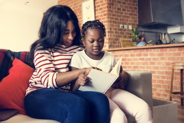 African mother helping her daughter in doing her homework clipart