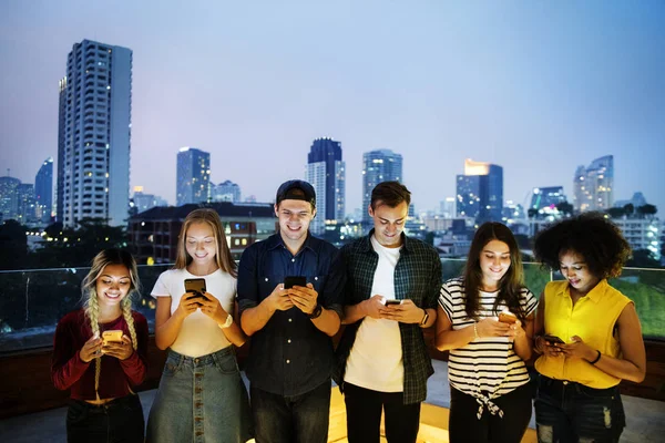 在城市景观中使用智能手机的年轻成年人快乐群体 — 图库照片