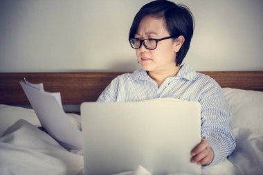 Yatakta bir dizüstü bilgisayar üzerinde çalışan bir kadın
