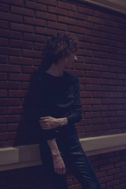 Bir tuğla duvar tarafından duran kadın