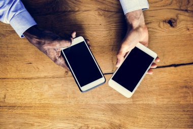 Bir akıllı telefon üzerinde ahşap masa holding eller