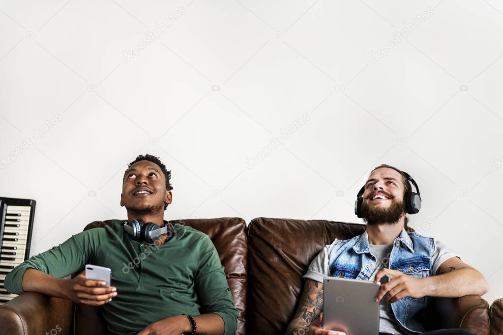 men friends sitting on sofa and listening to music 