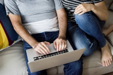 Mutlu çift evde rahatlatıcı ve dizüstü bilgisayar kullanarak