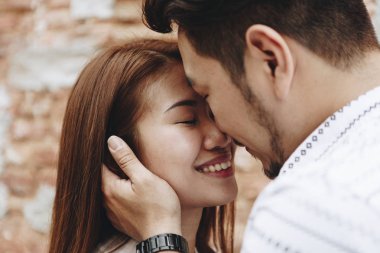 Bir tuğla duvar tarafından güzel Asyalı Çift