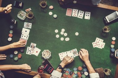 Bir grup insan içecekler ve para ile masada kartları ile poker oynamaya 