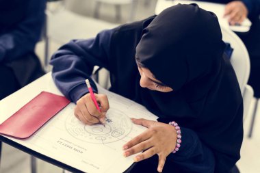 Ev görev yapıyor ve kağıda yazı genç Müslüman öğrenci kız 