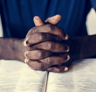 Afro-Amerikan erkek elleri açık bir İncil 'in üzerinde dinleniyor. 
