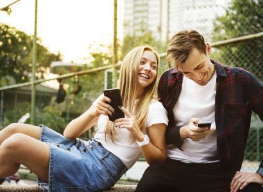 Mutlu sevimli genç çift parkta akıllı telefonlar birlikte kullanma