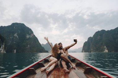 Couple taking selfie on a longtail boat clipart