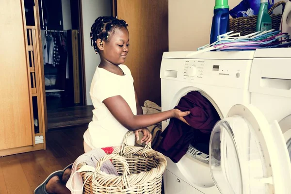 Young teen girl washing clothes using washing machine