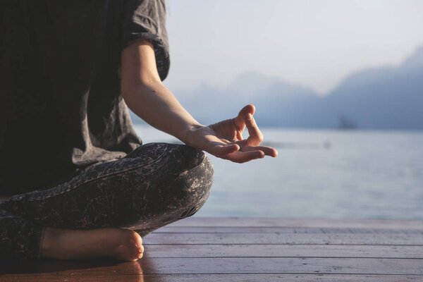 Woman practicing yoga by a lake