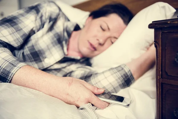 Bir Telefon Taşırken Yatakta Uyuyan Bir Kadın — Stok fotoğraf