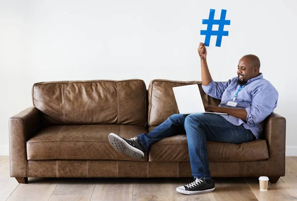 Homem Negro Relaxando Sofá Segurando Laptop Com Ícone Hashtag — Fotografia de Stock