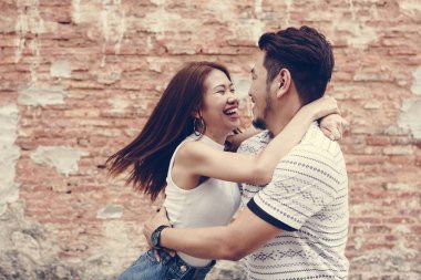 Bir tuğla duvar tarafından güzel Asyalı Çift