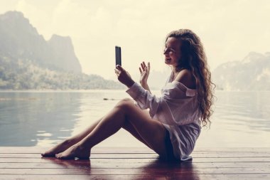 Telefonunu bir göl kenarında kullanan kadın