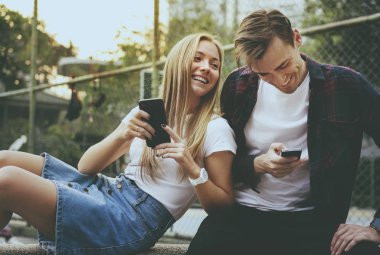 Mutlu sevimli genç çift parkta akıllı telefonlar birlikte kullanma