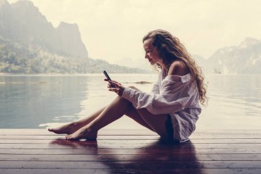 Telefonunu bir göl kenarında kullanan kadın