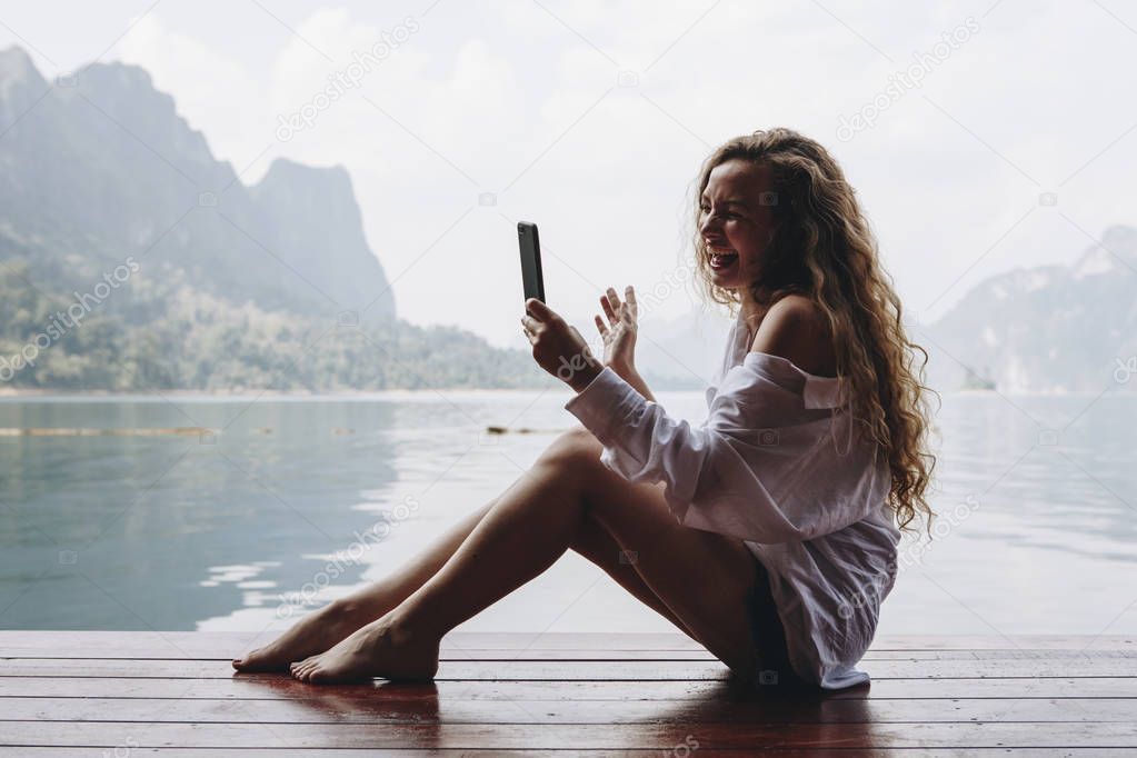 Woman using her phone by a lake