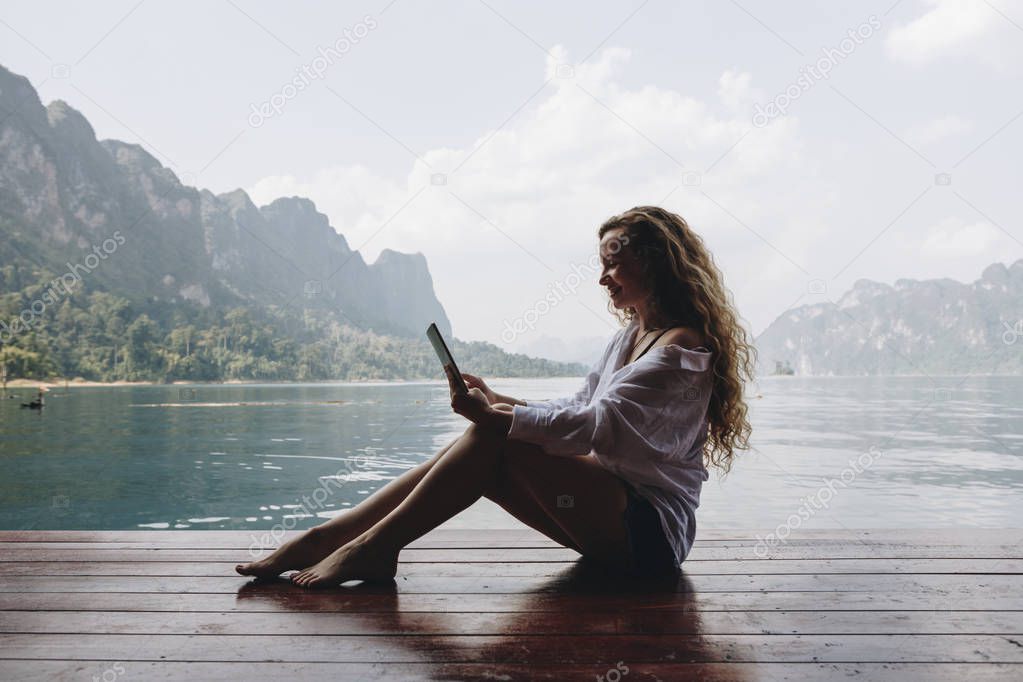 Woman using her phone by a lake