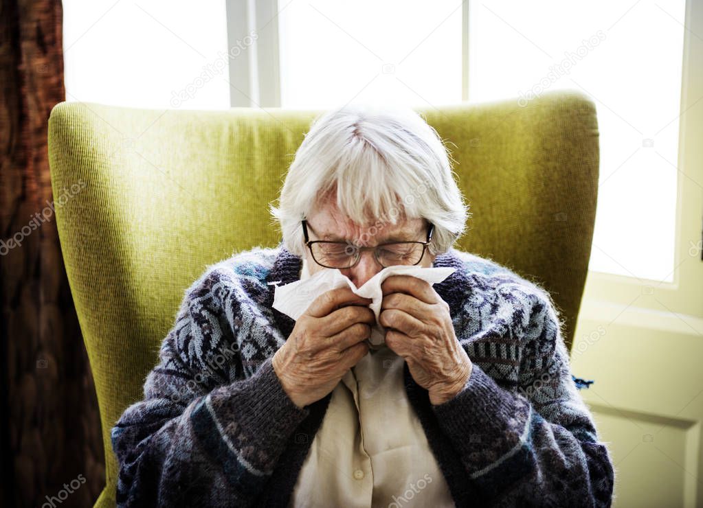 Senior woman sneezing at home 